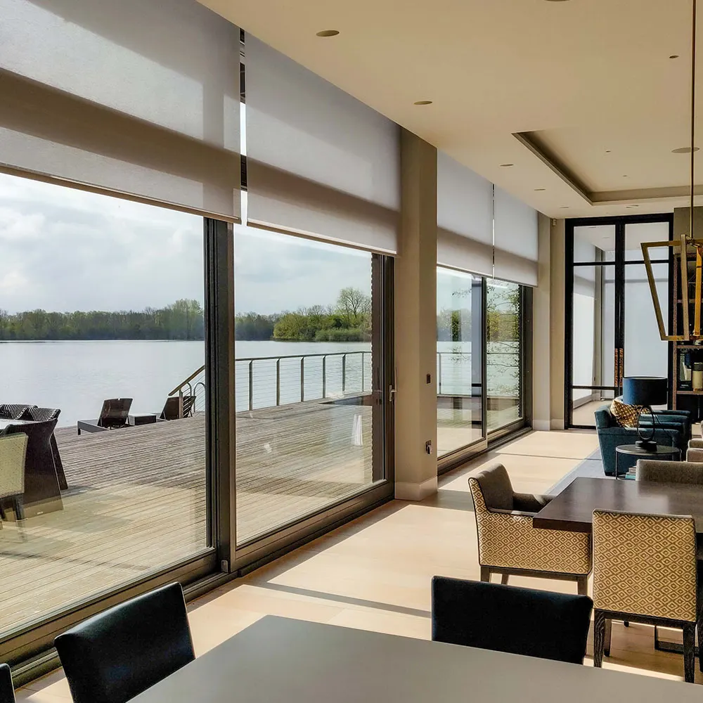 Open-plan living space with full-height glazing overlooking a lake