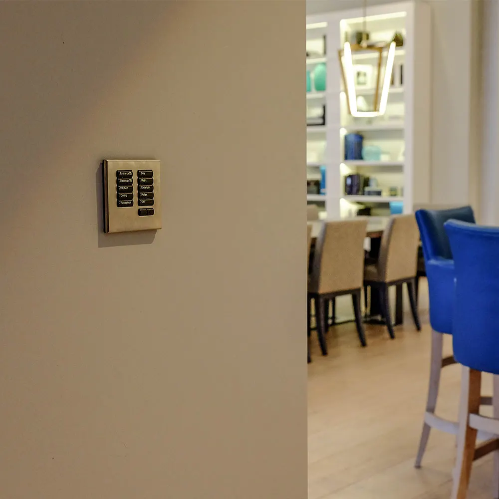 Engraved lighting keypad on a wall beside a dining area