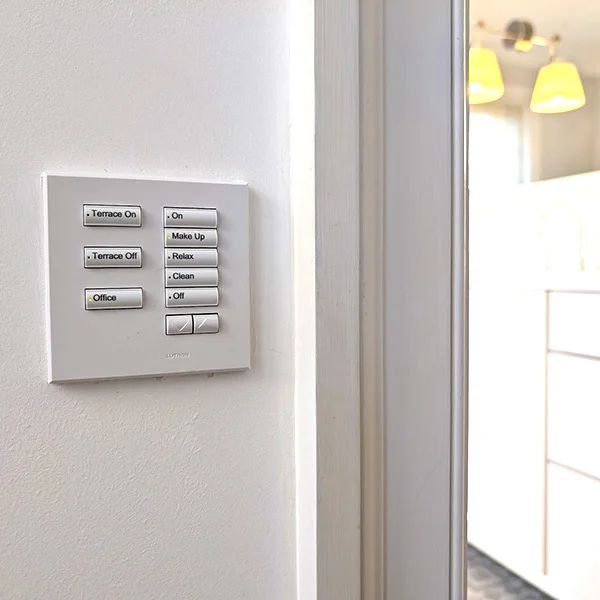 White Lutron seeTouch keypad with engraved buttons beside a doorway